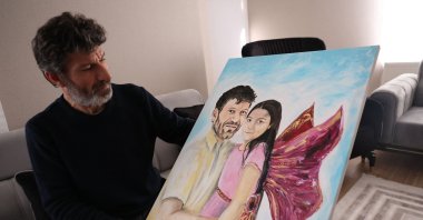 Turkish father Mesut Hançer, poses and holds a painting representing him and his daughter Irmak in his appartment as his family tries to rebuild, after losing their 15-years old daughter in the earthquake that devastated the southeastern region of Türkiye, Ankara, Türkiye, Feb. 25, 2023. (AFP Photo)