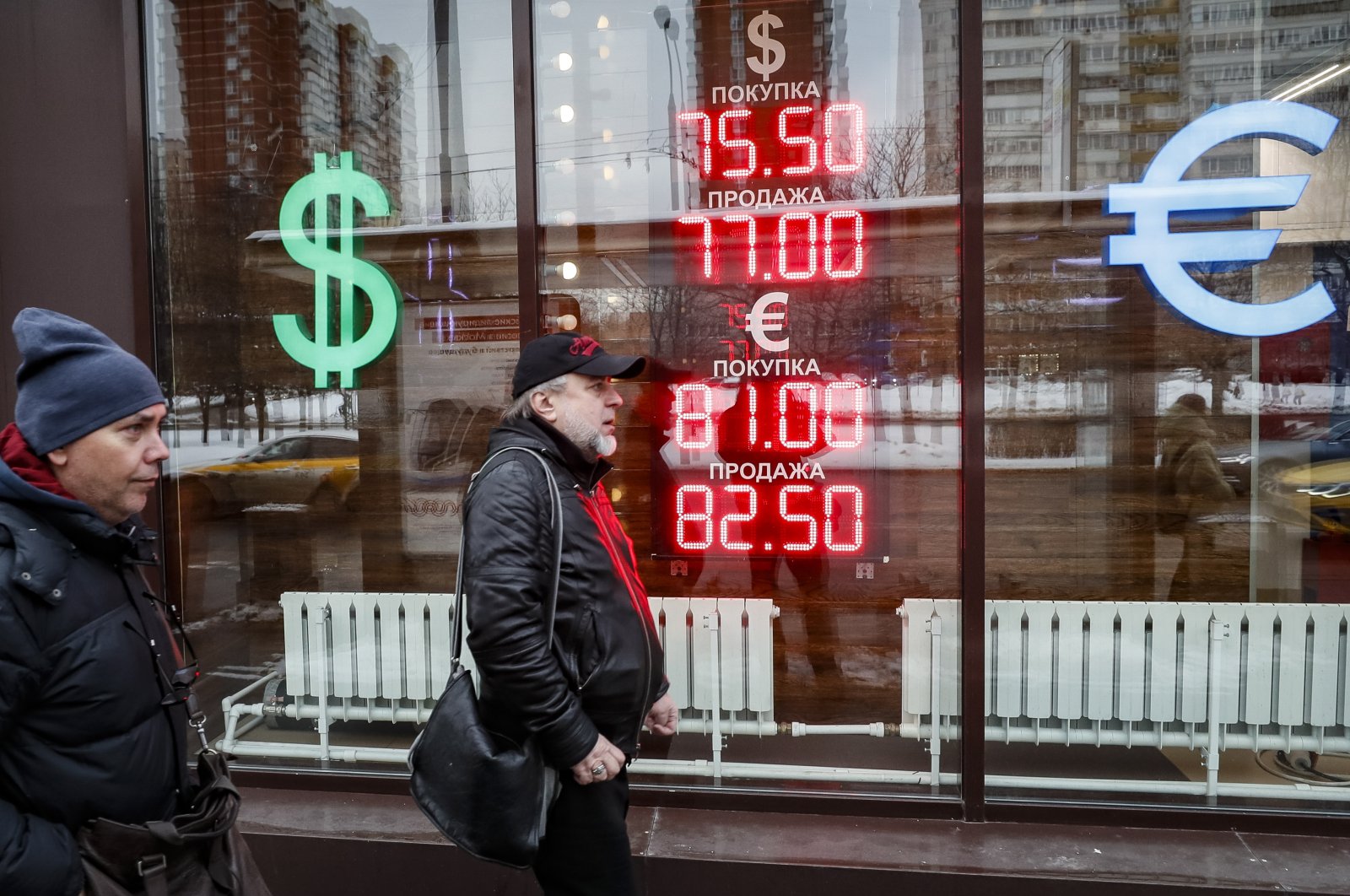 Russians walk in front of an exchange office with an electronic panel displaying currency exchange rates for U.S. dollars and euro against Russian Ruble in Moscow, Russia, Feb. 16, 2023. (EPA Photo)