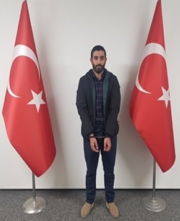 A handcuffed Ramazan Güneş poses between Turkish flags in an undisclosed location in this photo provided by Turkish authorities, Feb. 28, 2023. (AA Photo) 