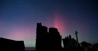 A handout picture taken by Ynys Enlli warden, Emyr Owen, shows the Aurora Borealis above buidlings on Ynys Enlli, known as Bardsey Island in English, an island off of the west coast of Wales, south west of Pwllheli, Feb. 26, 2023. (AFP Photo)