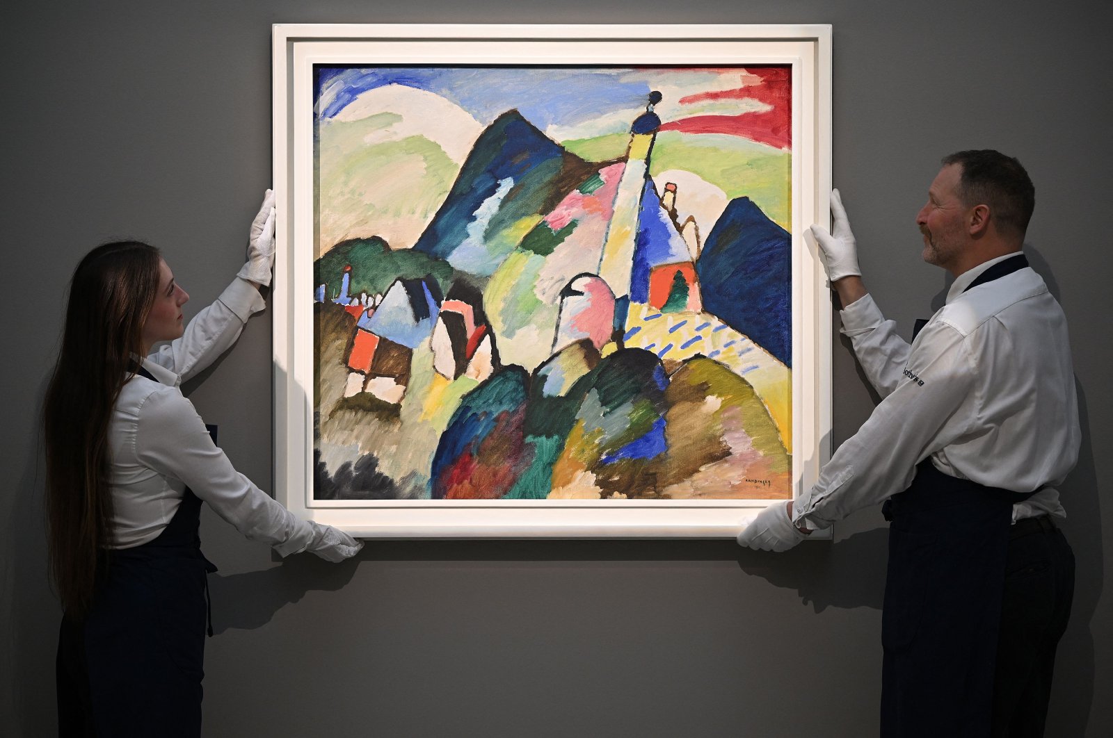 Employees poses with an artwork entitled &#039;Murnau mi Kirche II&#039; (Murnau with Church II) by Wassily Kandinsky, during a photocall at Sotheby&#039;s auction house in central London, U.K., Feb. 22, 2023. (AFP Photo) 