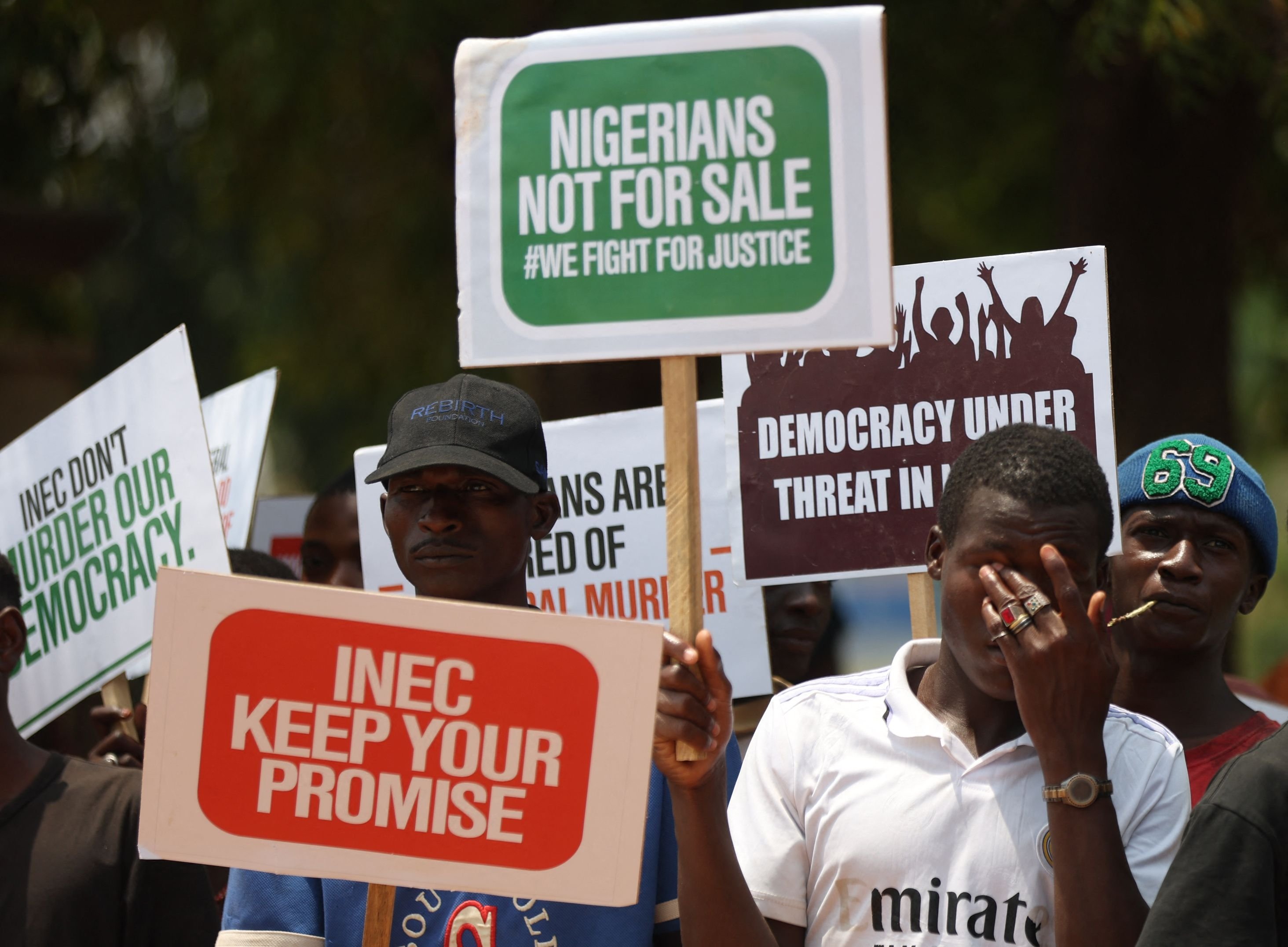 Sekelompok orang membentangkan plakat untuk memprotes hasil pemilihan presiden 2023 dan munculnya calon Kongres Semua Progresif (APC) Bola Tinubu sebagai presiden terpilih, Abuja, Nigeria, 1 Maret 2023. (AFP Photo)
