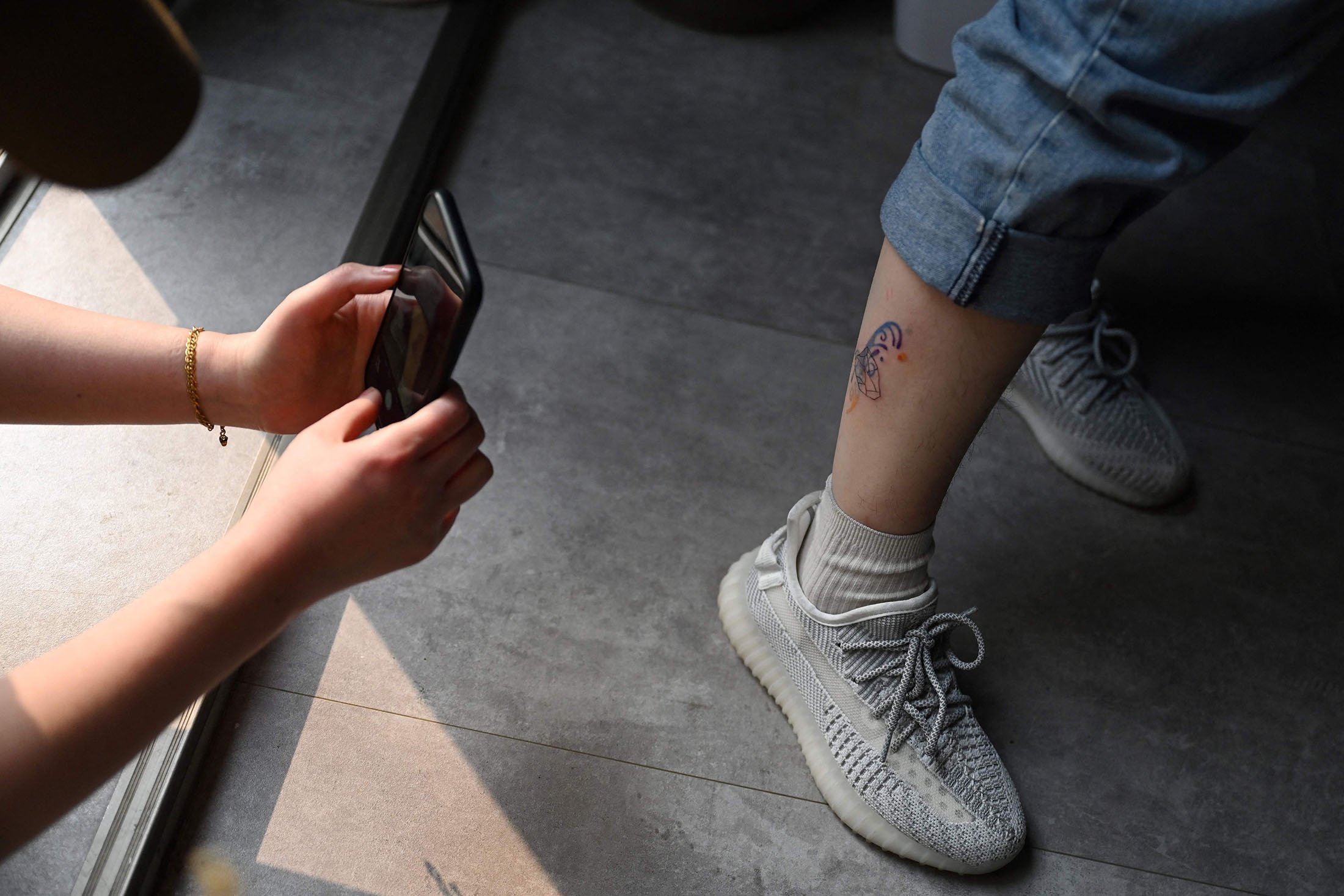 Artis tato Tiongkok Song Jiayin mengambil foto tato baru di kaki kliennya Liao Jingyi di studionya di Beijing, Tiongkok, 27 Februari 2023. (Foto AFP)
