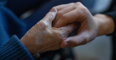 An elderly person holding a young man&#039;s hand. (Shutterstock Photo)