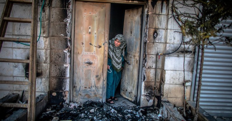 A Palestinian woman looks outside her door that was torched by Jewish settlers in the West Bank town of Huwara, occupied Palestine, Feb. 28, 2023. (Getty Images Photo)