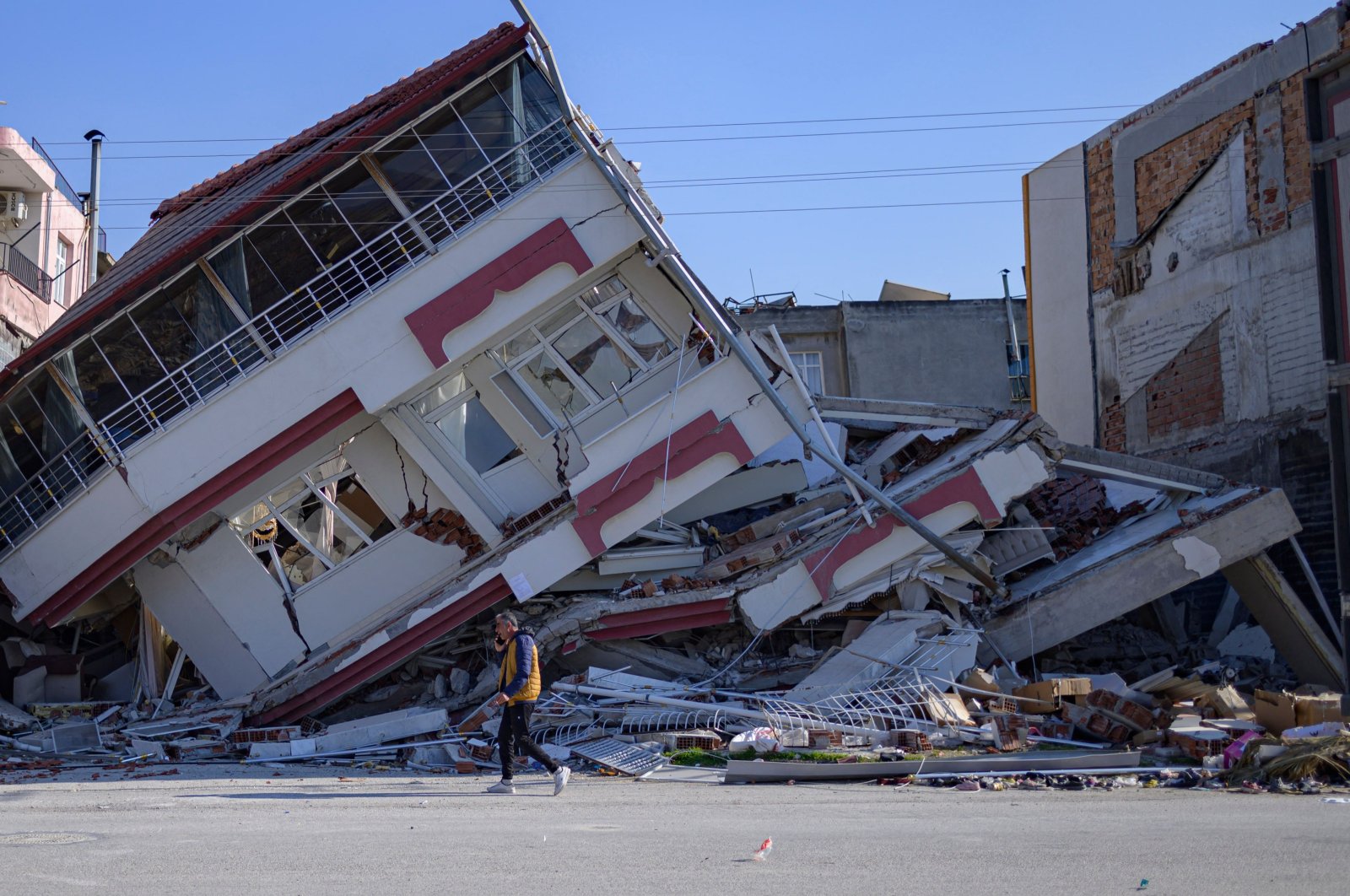A man walks in front of a destroyed building in Samandağ, south of Hatay, Türkiye on Feb. 16, 2023, days after a 7.7-magnitude struck the border region of Türkiye and Syria. (AFP Photo)
