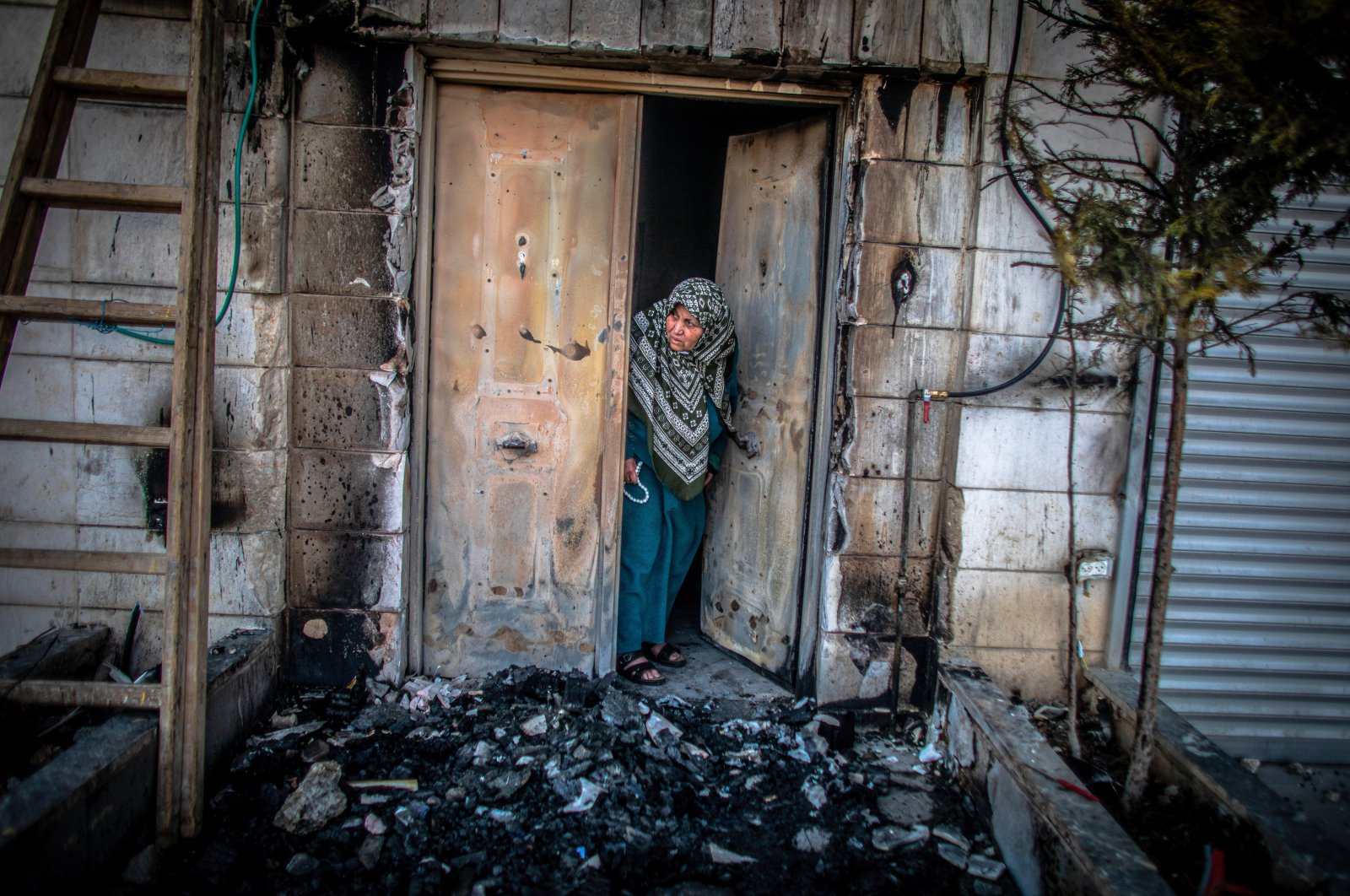 A Palestinian woman looks outside her door that was torched by Jewish settlers in the West Bank town of Huwara, occupied Palestine, Feb. 28, 2023. (Getty Images Photo)