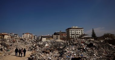 Hasan Arslan, his wife Havva and children Saltuk and Fatmagül walk among what remains of their home, in the aftermath of a deadly earthquake in Nurdaği, Türkiye, March 4, 2023. (Reuters Photo)