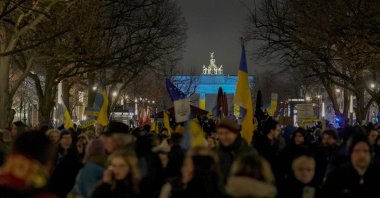 Protestors arrive at the Brandenburg Gate, illuminated in Ukrainian colors, during a demonstration to mark the first anniversary of Russia&#039;s full-scale invasion of Ukraine, in Berlin, Germany, Feb. 24, 2023. (AP Photo)
