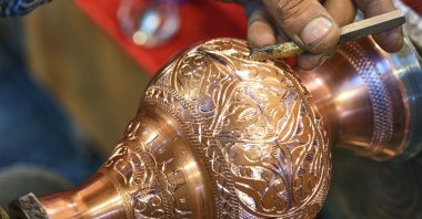 A coppersmith works on engraving a handcrafted item. (Shutterstock Photo)