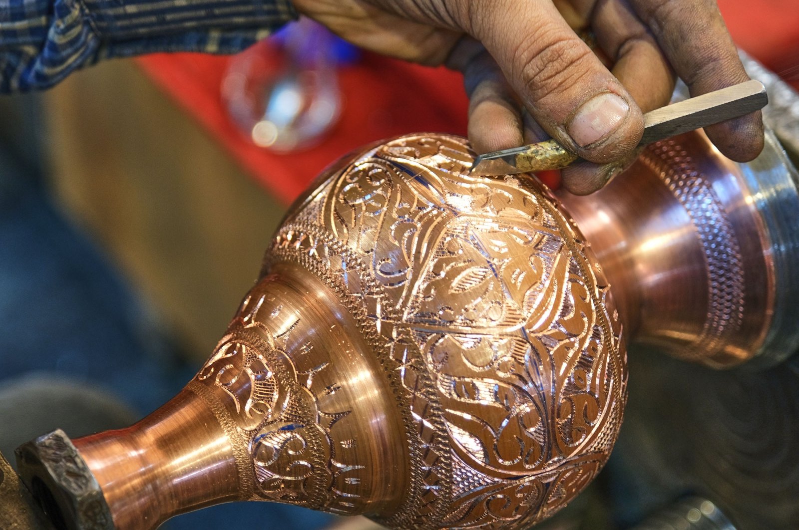 A coppersmith works on engraving a handcrafted item. (Shutterstock Photo)
