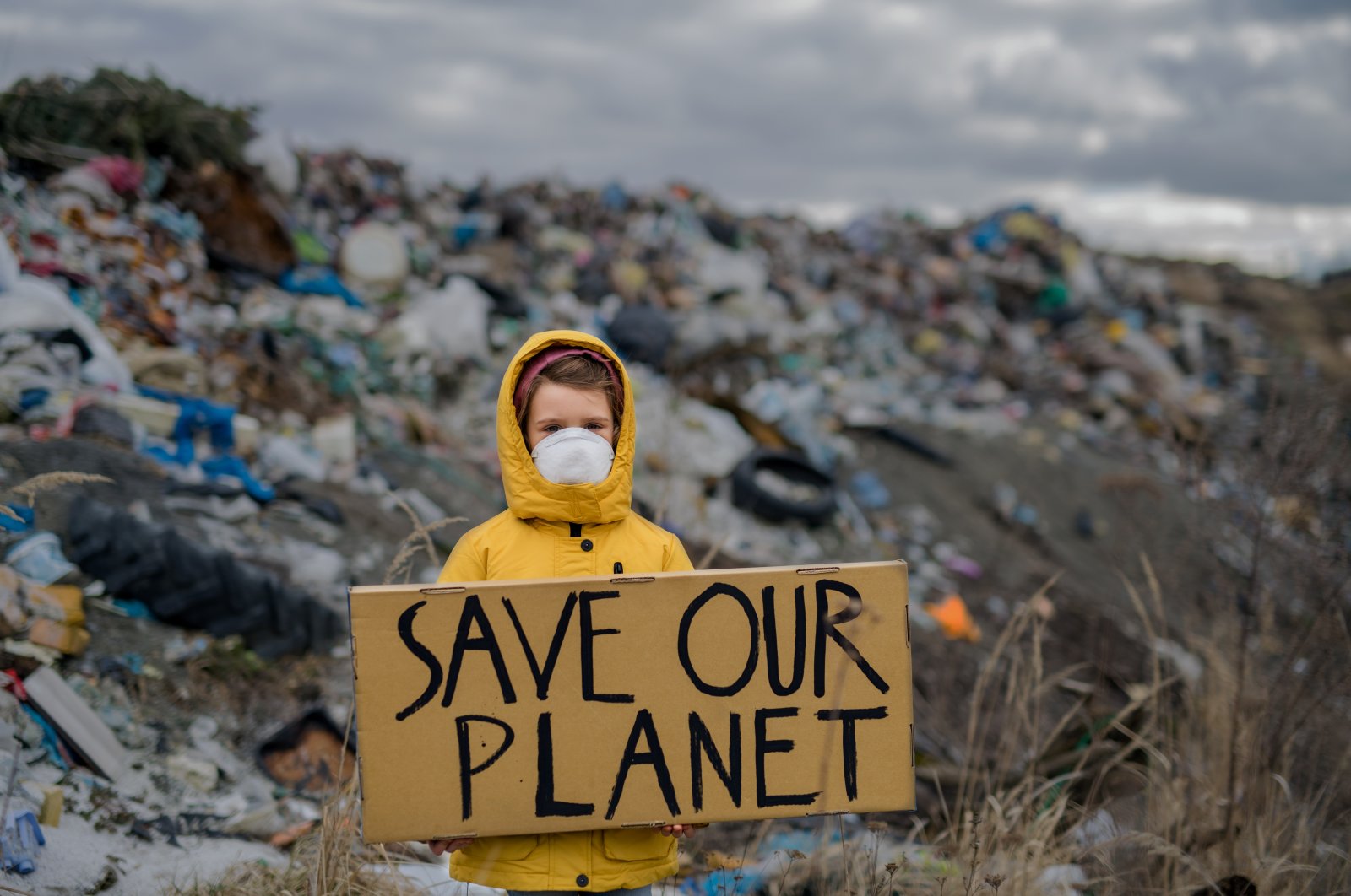 A child holding &#039;Save our Planet&#039; poster on landfill, environmental pollution, March 8, 2023. (Shutterstock Photo)