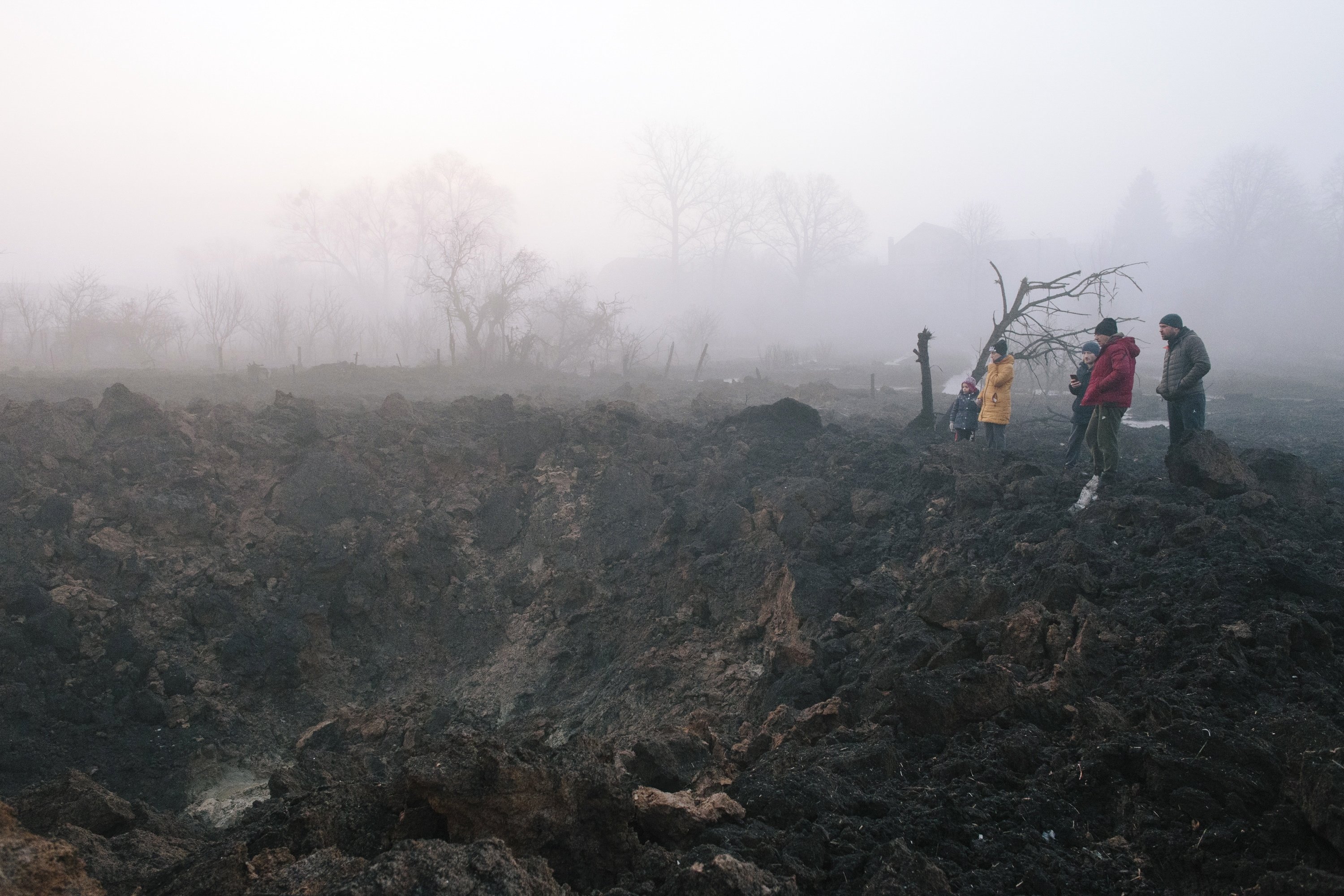 Penduduk setempat berkumpul di sekitar kawah setelah roket menghantam lingkungan Pisochyn di luar Kharkiv, Ukraina, 9 Maret 2023. (Foto EPA)