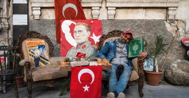 Serkan Sincan, 51, poses with a Quran found in the rubble of a collapsed building in front of his antique shop in the historic part of Antakya, Hatay, Türkiye, March 7, 2023. (AFP Photo)