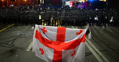 A demonstrator holds a Georgian flag in front of police, Tbilisi, Georgia, March 9, 2023. (Reuters Photo)
