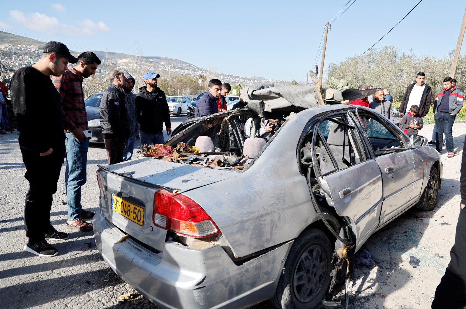 People look at a damaged car where three Palestinian men were killed during an Israeli operation, Jenin, Israeli-occupied West Bank, March 9, 2023. (Reuters Photo)