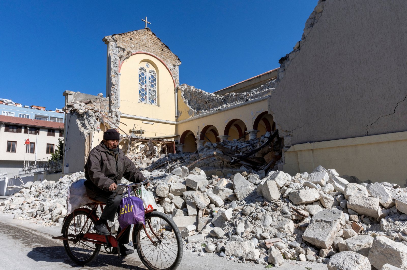 A man rides his bike past a collapsed Roman Catholic church in the aftermath of the deadly earthquake in Iskenderun, a coastal town of Hatay province, Türkiye, Feb. 14, 2023. (Reuters photo)