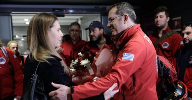 Gökçe Över (L), a Turkish consulate official in Thessaloniki, give flowers to Greek search and rescue teams who returned from Türkiye, in Thessaloniki, Greece, Feb. 16, 2023. (AA Photo)