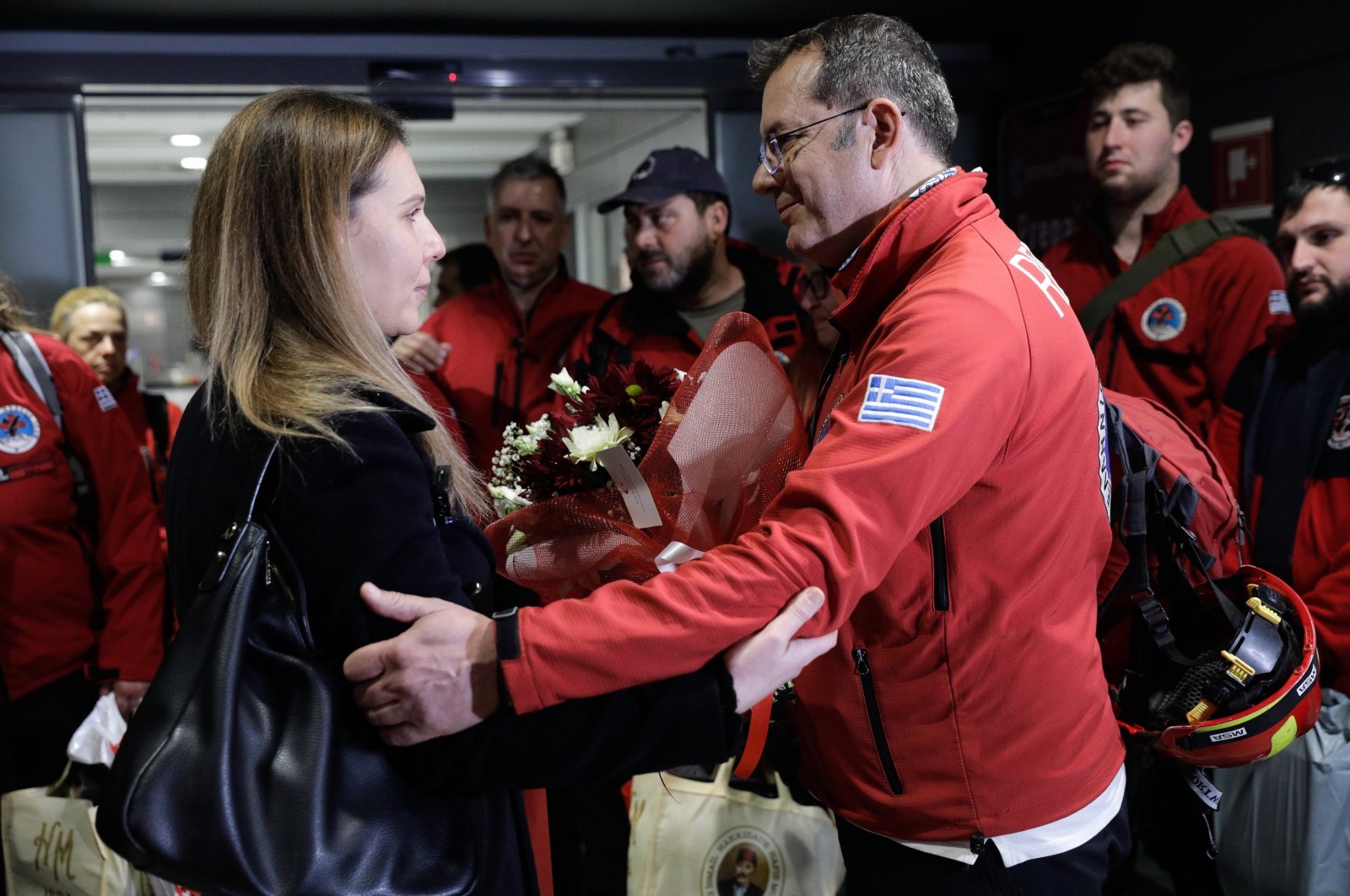 Gökçe Över (L), a Turkish consulate official in Thessaloniki, give flowers to Greek search and rescue teams who returned from Türkiye, in Thessaloniki, Greece, Feb. 16, 2023. (AA Photo)