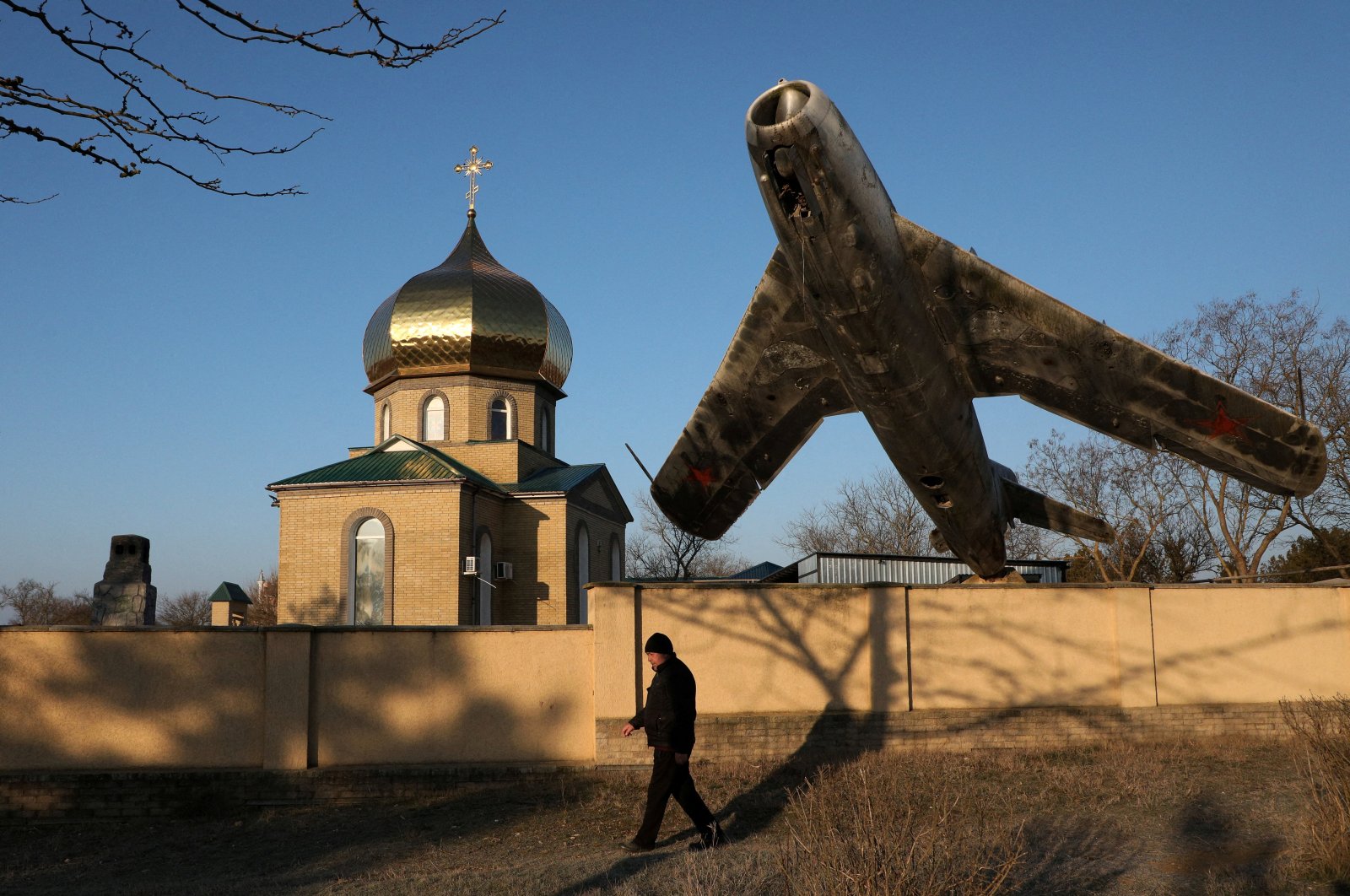 A man walks past a monument to a Soviet MiG-17 fighter aircraft installed next to a church in the village of Okhotnykove, Crimea March 2, 2023. (Reuters File Photo)