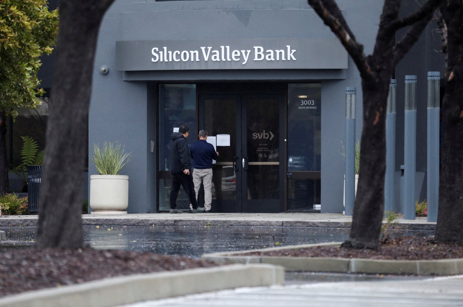 A man puts a sign on the door of the Silicon Valley Bank as an onlooker watches at the bank’s headquarters in Santa Clara, California, U.S. March 10, 2023. (Reuters Photo)