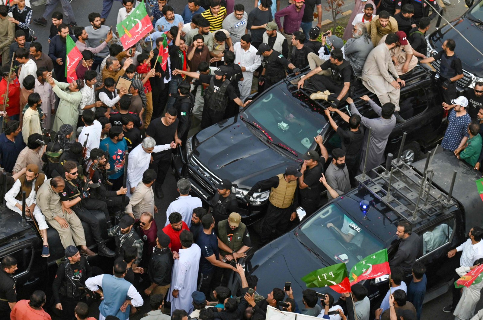Security personnel and supporters escort a vehicle (left) carrying Pakistan&#039;s former prime minister Imran Khan during an election campaign rally for Punjab provincial assembly to be held next month, in Lahore on March 13, 2023. (AFP Photo)