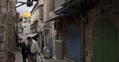 A Jewish man passes a row of Palestinian shops closed in the Old City of Jerusalem as part of a general strike, a day after 10 Palestinians were killed in an Israeli army raid in the West Bank, occupied Palestine, Feb. 23, 2023. (AP Photo)