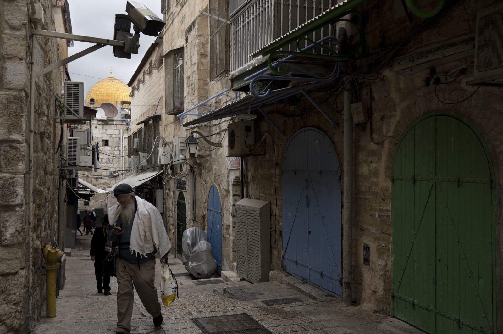 A Jewish man passes a row of Palestinian shops closed in the Old City of Jerusalem as part of a general strike, a day after 10 Palestinians were killed in an Israeli army raid in the West Bank, occupied Palestine, Feb. 23, 2023. (AP Photo)