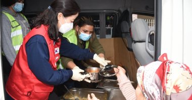 A member of a Korean volunteer team (L) hands a warm meal to an earthquake survivor in Osmaniye, southern Türkiye, March 15, 2023. (IHA Photo)