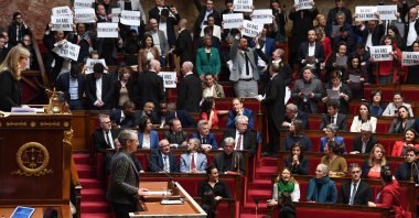 Members of Parliament of left-wing coalition NUPES (New People's Ecologic and Social Union) hold placards during the speech of France's Prime Minister Elisabeth Borne (center), as she confirms to force through pension law without parliament vote during a session on the government's pension reform at the lower house National Assembly, in Paris, France, March 16, 2023. (AFP Photo)