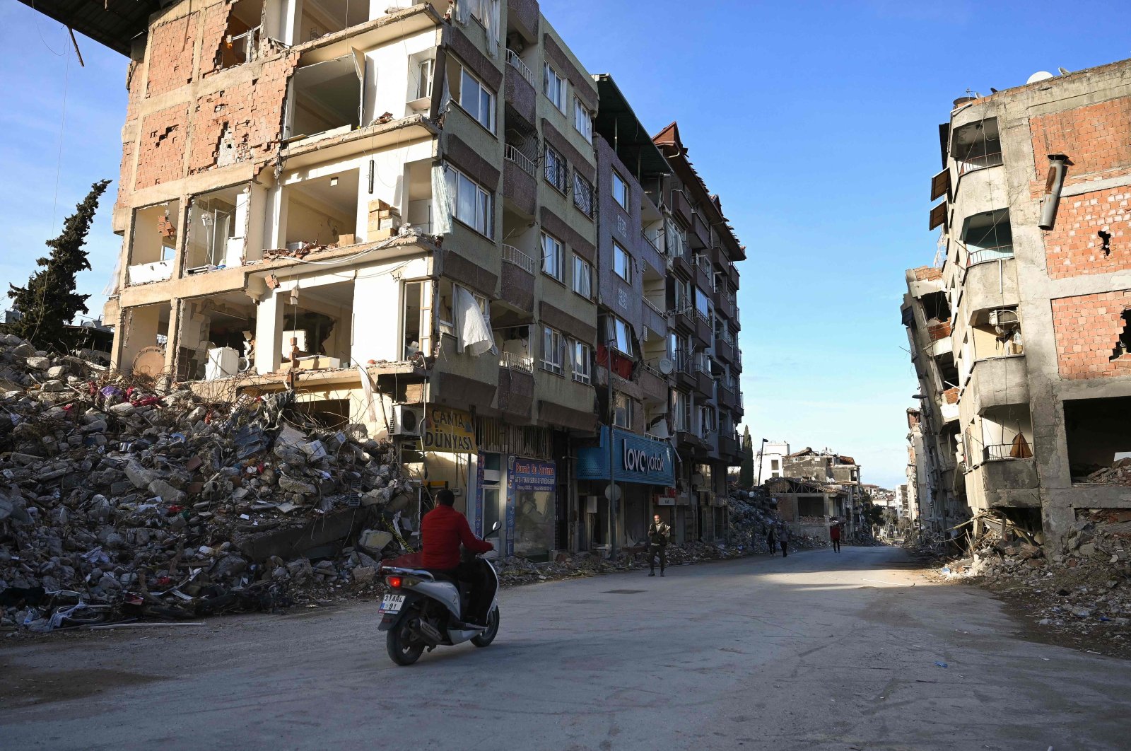 A man rides his motorcycle in a destroyed neighborhood among the rubble of collapsed buildings in Hatay, March 7, 2023, a month after a massive earthquake struck southeastern Türkiye. (AFP Photo)