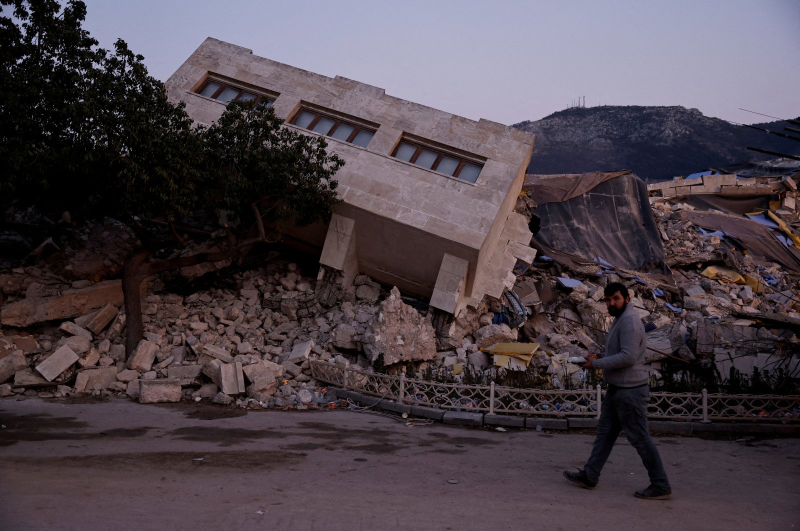 A man walks past a collapsed building and rubble, in the aftermath of a deadly earthquake, in Antakya, Hatay province, southeastern Türkiye, Feb. 21, 2023. (Reuters Photo)