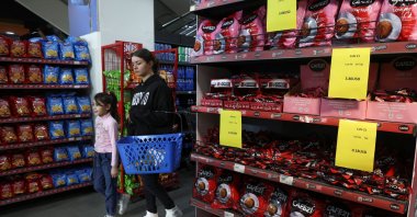 People pass near signs showing prices of coffee in U.S. dollars inside a supermarket in Beirut, Lebanon March 9, 2023. (Reuters Photo)