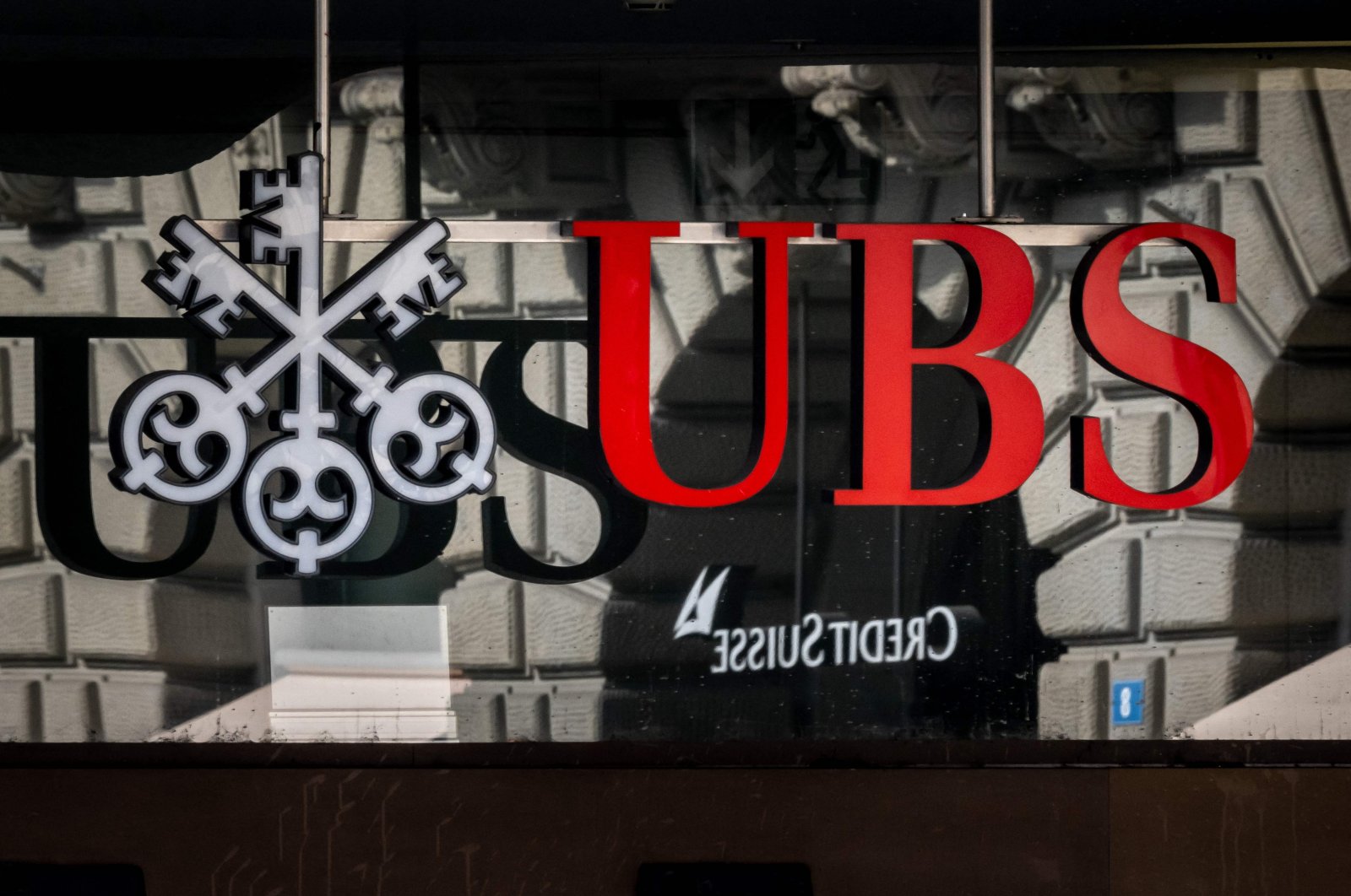 A photograph shows a logo of Swiss giant bank UBS in front of a logo of Credit Suisse bank in Zurich, Switzerland, March 19, 2023. (AFP Photo)