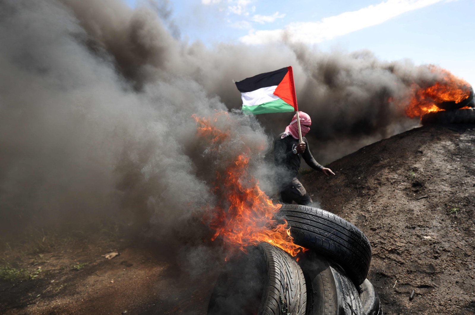 A Palestinian holds a national flag during a small protest against an Israel-Palestine meeting in Egypt, east of Gaza City, Palestine, March 19, 2023. (AFP Photo)