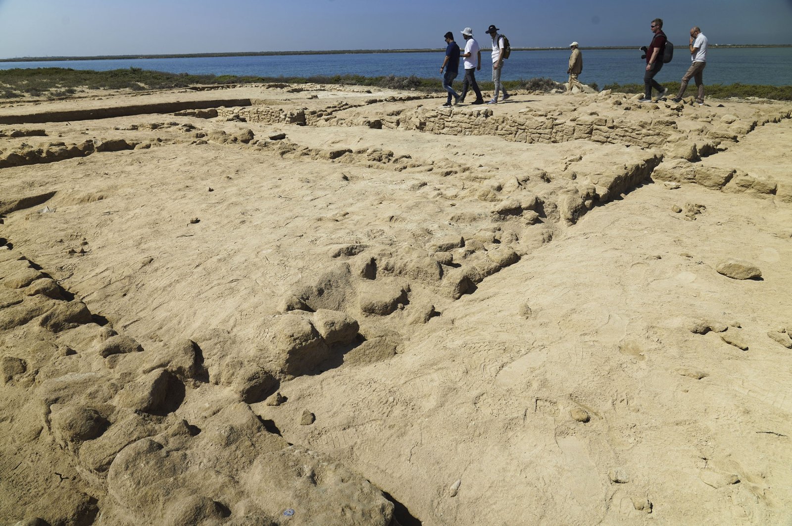 Archaeologists and journalists walk past uncovered ruins on Siniyah Island in Umm al-Quwain, United Arab Emirates, March 20, 2023. (AP Photo)