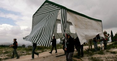Israeli activists carry a tent in the abandoned Jewish settlement of Homesh, northern West Bank, March 27, 2007. (Reuters Photo)