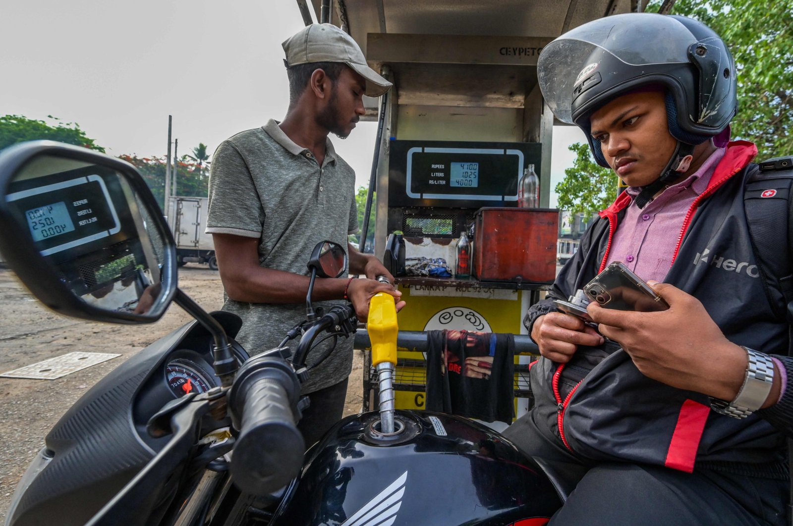 A worker fills petrol in a motorbike at a fuel station on March 21, 2023. - Sri Lanka must not allow entrenched corruption to undermine a bailout for its bankrupt economy, the IMF said on March 21, 2023, after signing off on a $3 billion loan for the crisis-hit nation. (AFP Photo)