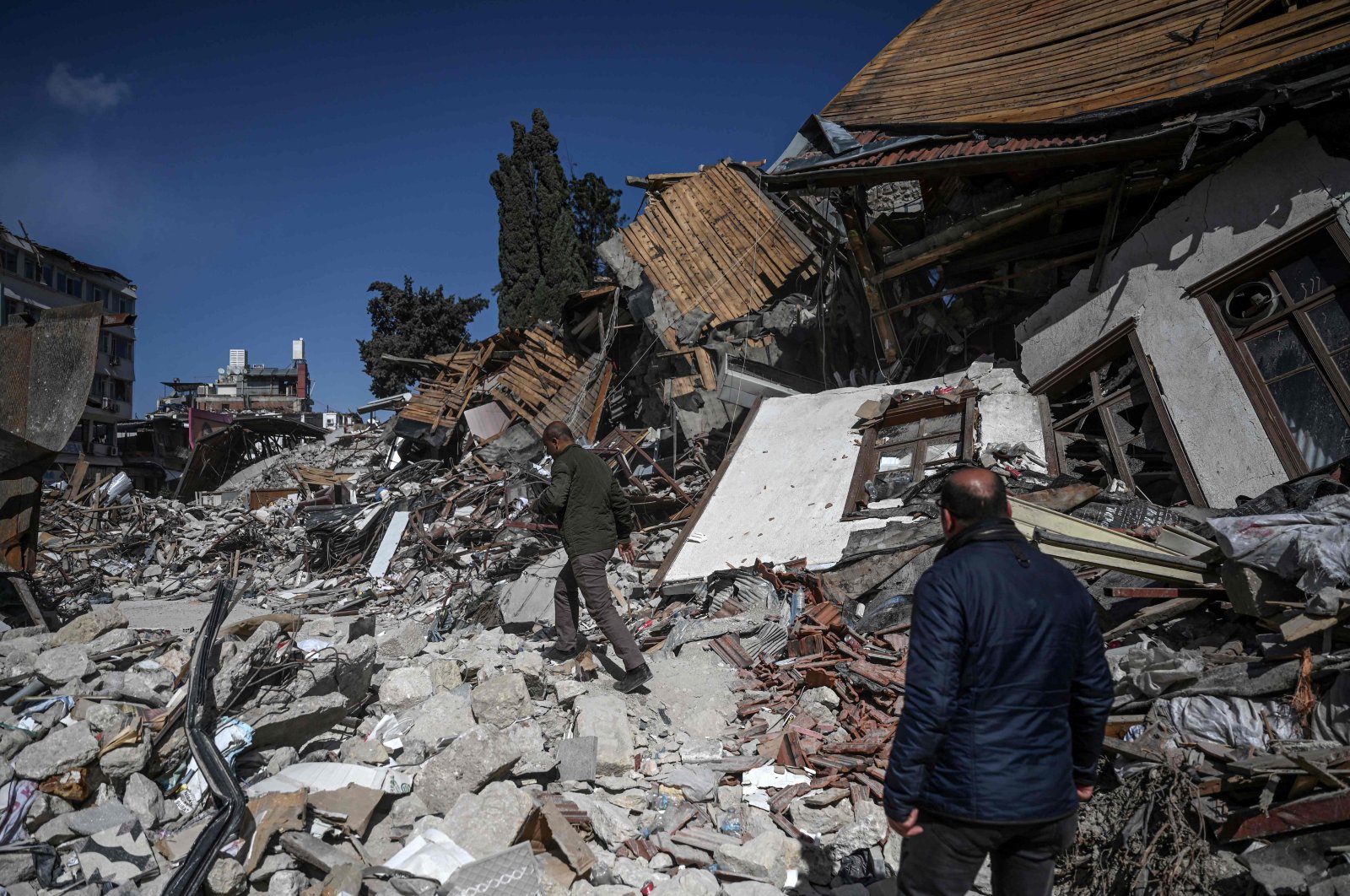 People walk among the rubble of collapsed buildings in Hatay, southern Türkiye, March 6, 2023. (AFP Photo)