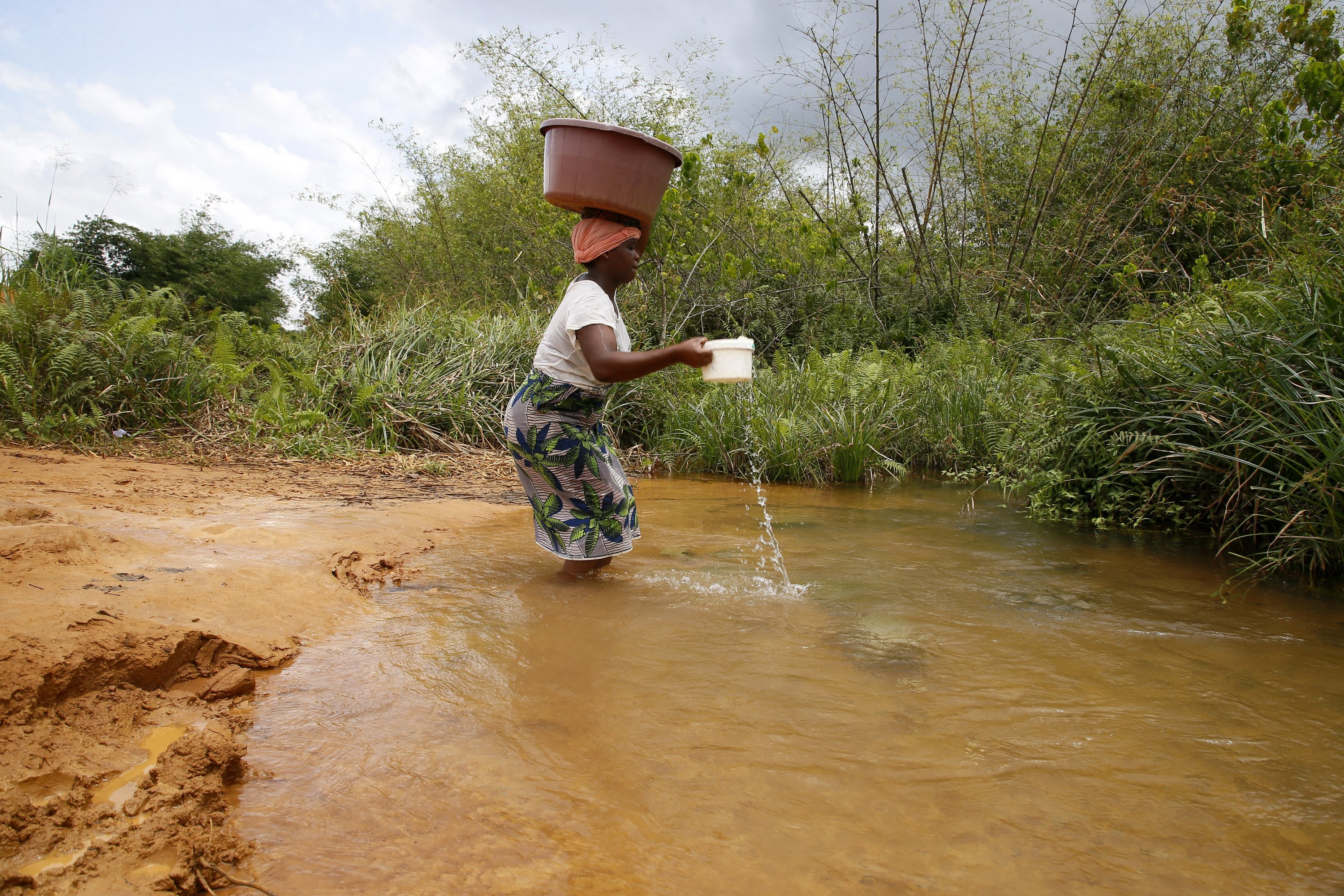 Seorang perempuan mengisi ember dengan air sungai untuk kebutuhan air sehari-hari di Abidjan, Pantai Gading, 21 Maret 2023.(Foto EPA)