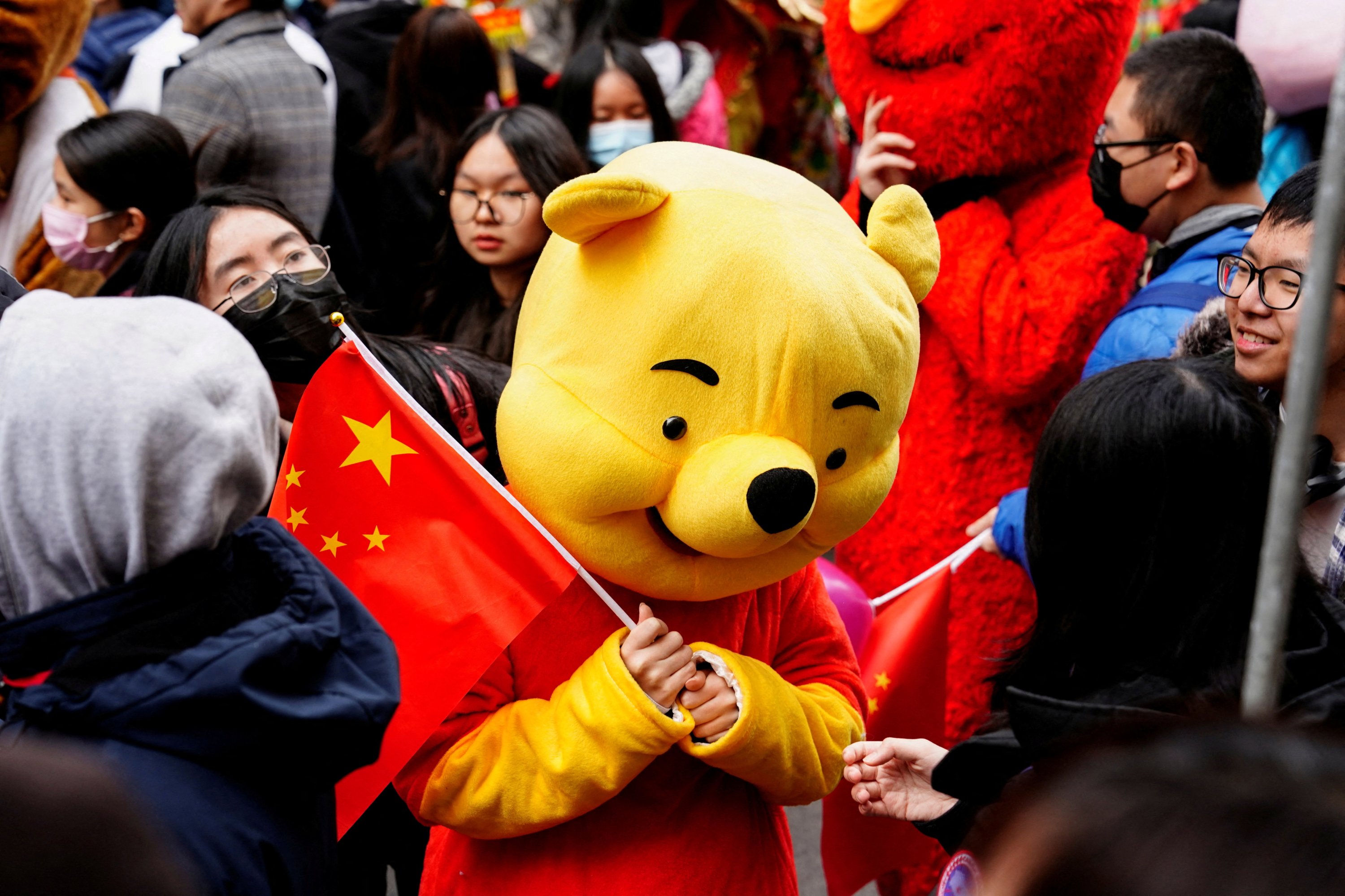 Seorang peserta pawai dengan kostum Winnie the Pooh mengibarkan bendera Tiongkok sebelum pawai Tahun Baru Imlek merayakan Tahun Kelinci di kawasan Chinatown di New York, AS, 12 Februari 2023. (Foto Reuters)
