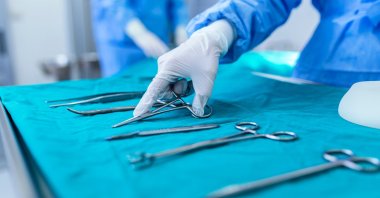 Surgical instruments and a group of surgeons operate on a patient in a surgical theater, March 22, 2023. (Shutterstock Photo)
