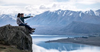 A young couple sits on a rock in New Zealand. (Shutterstock Photo)