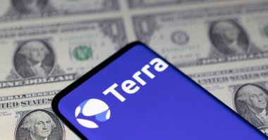 A smartphone with the Terra logo is placed on displayed U.S. dollars in this illustration taken May 11, 2022. (Reuters Photo)