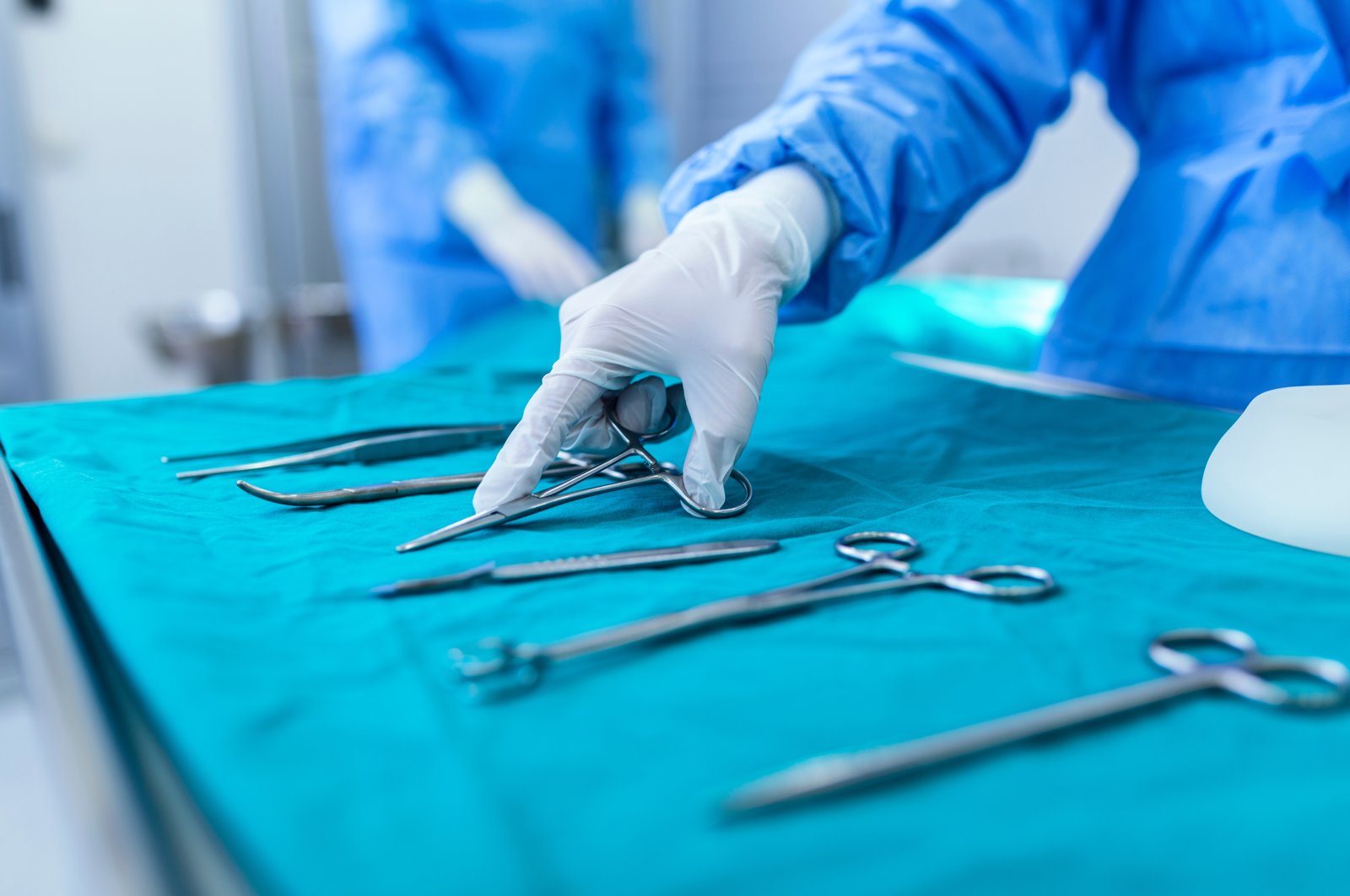 Surgical instruments and a group of surgeons operate on a patient in a surgical theater, March 22, 2023. (Shutterstock Photo)