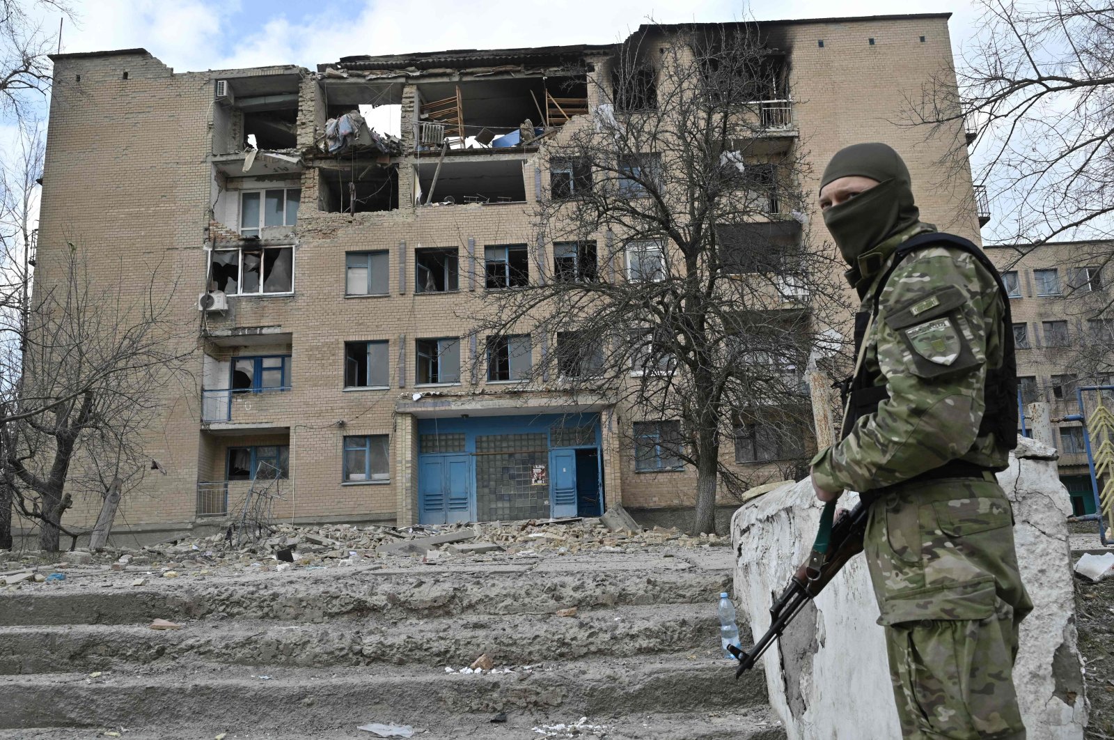 A Ukrainian police officer stands in front of a partially destroyed building after an airstrike in the town of Rzhyshchiv, in the Kyiv region, Ukraine, March 22, 2023. (AFP Photo)