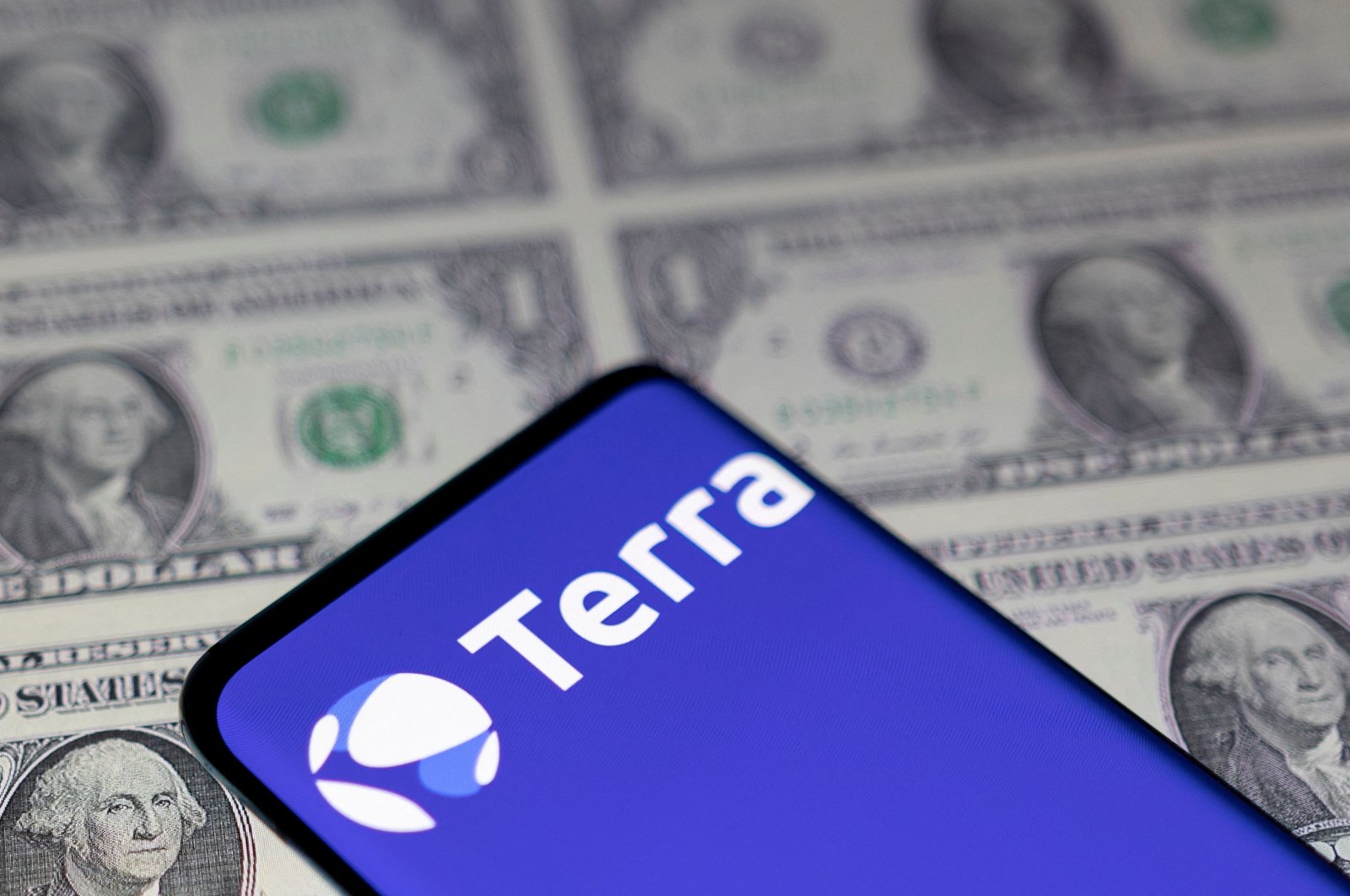 A smartphone with the Terra logo is placed on displayed U.S. dollars in this illustration taken May 11, 2022. (Reuters Photo)