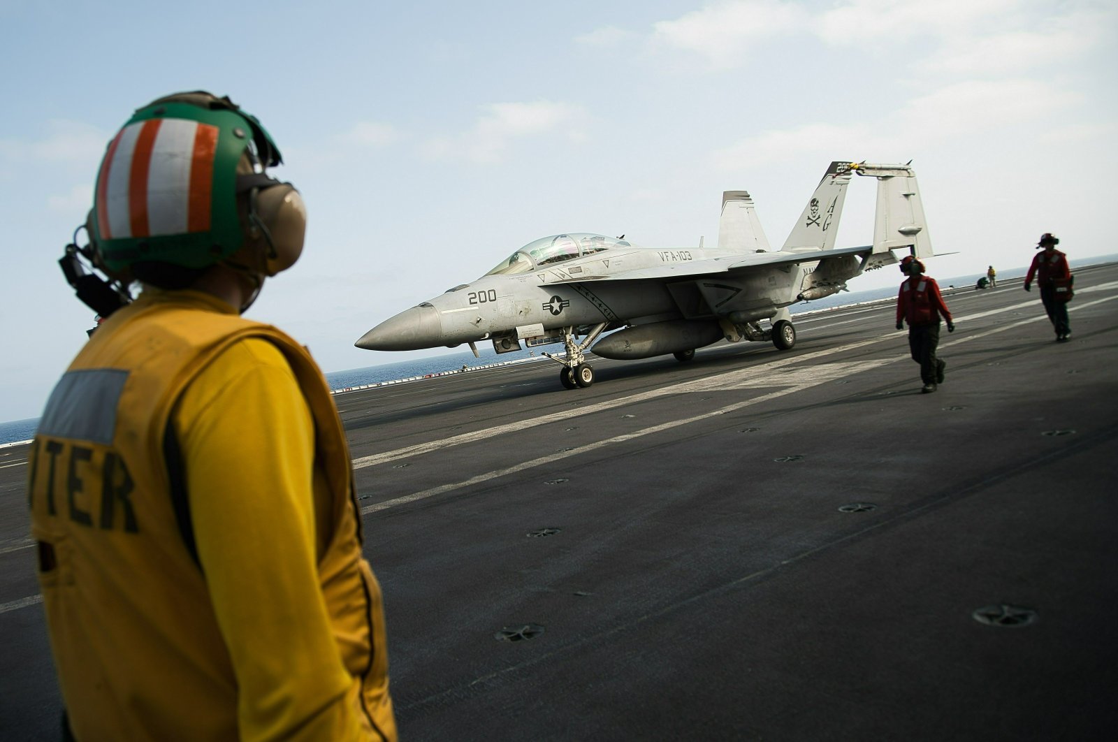 A crew member looks at a taxing F/A-18 fighter jet on the deck of the USS Abraham Lincoln aircraft carrier in the Persian Gulf, June 3, 2019. (AP Photo)