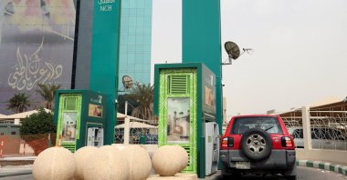 A man in a car withdraws money from an ATM outside the Saudi National Commercial Bank (NCB), in Riyadh, Saudi Arabia, March 18, 2020. (Reuters Photo)