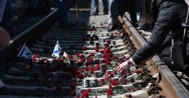 Participants place flowers on railway tracks at the old railway station in Thessaloniki after taking part in a march to mark the departure of the first train deporting Greek Jews from Thessaloniki to Auschwitz-Birkenau concentration camp, March 19, 2023. (AFP Photo)